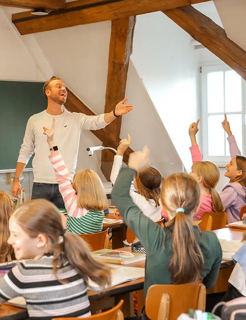 Lachender Lehrer vor Schulklasse